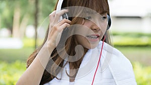 asian woman with headphones. young female girl listening to music in public park