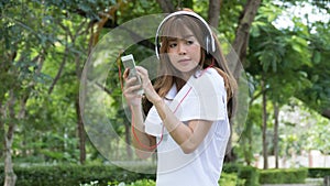 asian woman with headphones. young female holding mobile smart