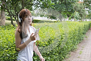 asian woman with headphones. young female holding mobile smart