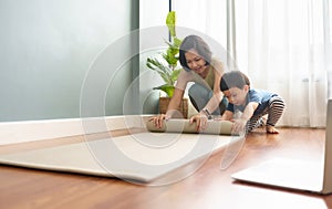 Asian woman and her little boy rolling yoga mat