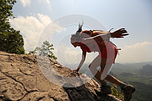 Asian woman hiker climbing rock on mountain peak cliff