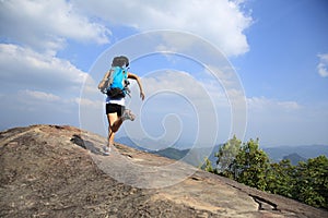 Asian woman hiker running on mountain peak cliff