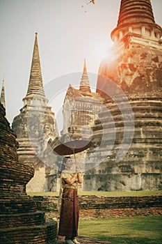 asian woman holding bamboo umbrella standing against stupa in ancient temple of ayutthaya world heritage site of unesco central of