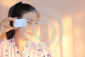 Asian woman holding a blank business card or credit card with copy space for your text.