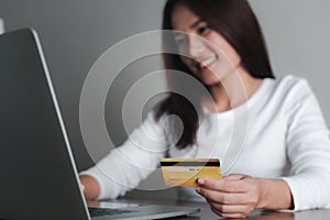 Asian woman holding credit card and using laptop computer,  e-commerce, internet banking, Online shopping and spending via credit