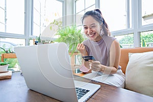 Asian woman is holding credit card and using smartphone shopping online at home. Online shopping, e-commerce, internet banking,