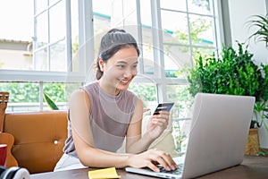 Asian woman is holding credit card and using smartphone shopping online at home. Online shopping, e-commerce, internet banking,