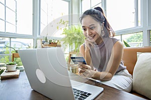 Asian woman is holding credit card and using smartphone shopping online at home. Online shopping, e-commerce, internet banking,