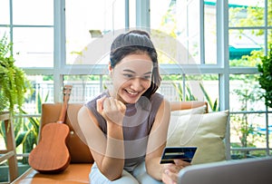 Asian woman is holding credit card and using smartphone shopping online at home. Online shopping  e-commerce  internet banking