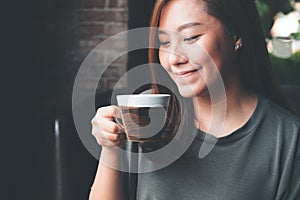 An Asian woman holding and drinking hot coffee with feeling good in vintage cafe