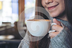 An Asian woman holding and drinking hot coffee in winter time