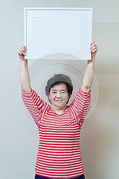 Asian woman holding empty white picture frame in studio shot, sp