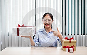 Asian woman holding a gift box Glad to be the giver of surprise with excitement, joy and smiles on the holidays, Christmas,
