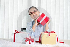 Asian woman holding a gift box Glad to be the giver of surprise with excitement, joy, and smiles on the holidays, Christmas,