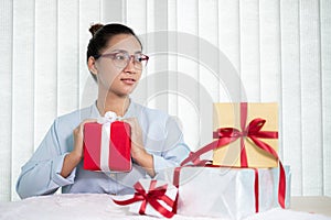 Asian woman holding a gift box Glad to be the giver of surprise with excitement, joy, and smiles on the holidays, Christmas,