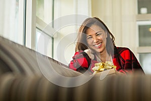 Asian woman holding a gift sitting on the sofa.