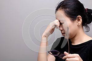 Asian woman holding glasses, suffer from having a strong headache and fever, poor sight, farsightedness, myopia