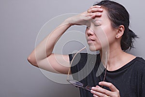 Asian woman holding her head, suffer from having a strong headache and fever, poor sight, farsightedness, myopia