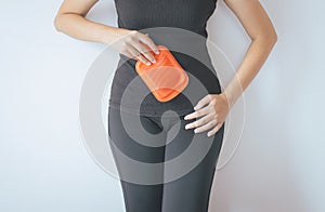 Asian woman holding hot water bag or bottle on her stomach ache lying on white blackground