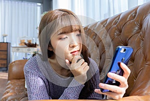 Asian woman holding mobile in her hands on the light background