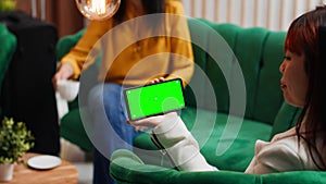 Asian woman holding phone with isolated greenscreen in lobby