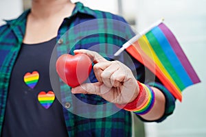 Asian woman holding red hert with rainbow flag, LGBT symbol rights and gender equality, LGBT Pride Month in June