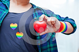 Asian woman holding red hert with rainbow flag, LGBT symbol rights and gender equality, LGBT Pride Month in June