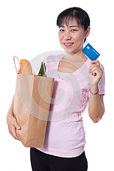 Asian woman holding a shopping bag full of groceries and credit