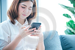 Asian woman holding smartphone with E-commerce Shopping online website Reading Online Article, Blog, vlog. Young Woman hands