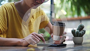Asian woman  holding smartphone sitting outdoors cafe. Portrait of young woman typing smartphone at coffee break.