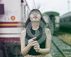 Asian woman holding tree branch gesturing at the train station