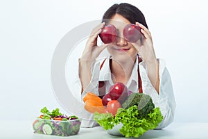 Asian woman holding vegetables and smiling on white background.