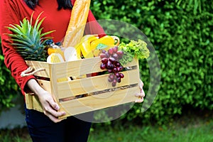 Asian woman holding wooden basket with vegetables. fresh vegetables in a basket. picnic in the garden. Stay at home. Enjoy cooking