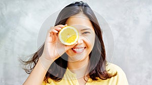 Asian woman holding a yellow lemon, selective focus