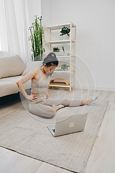 Asian woman at home exercising stretching and yoga repeating challenging exercises with video online watching on laptop