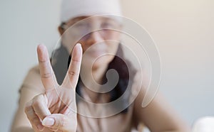 Asian woman injured for accident wearing bandage and smiling with happy face doing victory sign with fingers