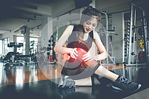 Asian woman injuries during workout at knee in fitness gym. Medical and Healthcare concept. Exercise and Training theme. photo