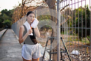 Asian woman jogging and running outdoors in nature. Asian women sweat with a towel after an evening jog