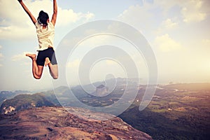 Asian woman jumping on mountain peak cliff