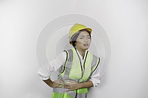 Asian woman labor worker wearing a safety helmet and vest hold hand on stomach suffers pain isolated white background.
