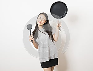 Asian woman with ladle and a pan on white background.