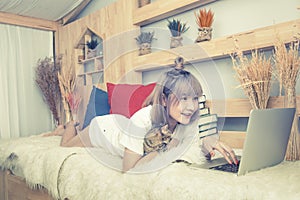 Asian woman lady in casual dress lay down on bed and relax with cat and play on laptop,process in vintage style