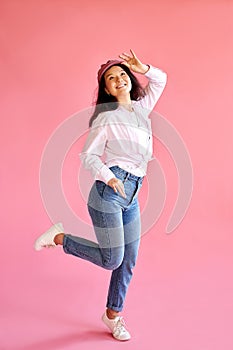 Asian woman laughs at something funny with pleasure, isolated over pink background