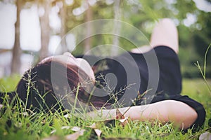 An Asian woman lay down on grass field with feeling relax and green nature