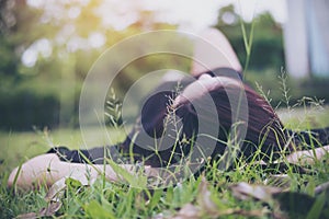 An Asian woman lay down on grass field with feeling relax and green nature