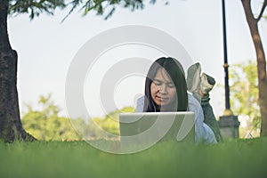 Asian woman lay down green garden park using laptop working outdoor home office. Happiness Woman smile working Freelance on laptop