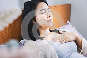 Asian woman laydown in bed having problem with heartburn from acid reflux difficult to breathe after wakeup in morning