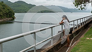 Asian woman leaning on railing looking at resevoir