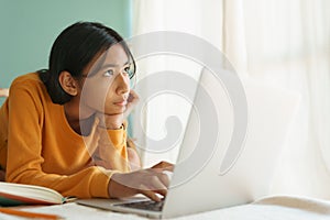 Asian woman learning online with a tutor via the internet with a laptop While looking outside the house in morning, Concept online