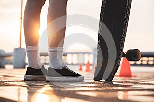 Asian woman leg on surf skate or skate board in outdoor Park at sunset.
